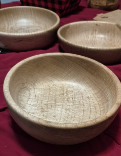 Three wooden bowls on a red quilted surface.