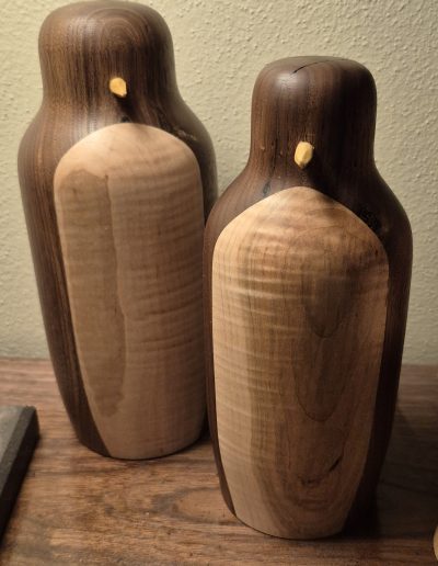 Two handcrafted wooden penguins with contrasting dark and light wood sections.